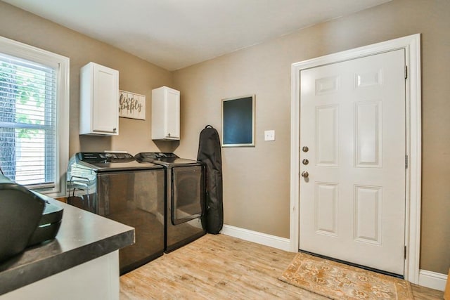 laundry area with washing machine and dryer, cabinets, and light wood-type flooring