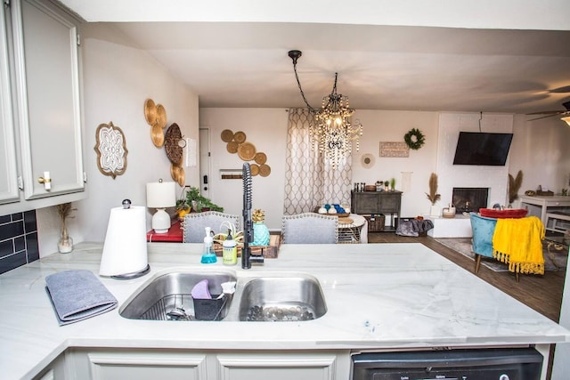 kitchen featuring white cabinets, sink, dishwashing machine, and an inviting chandelier