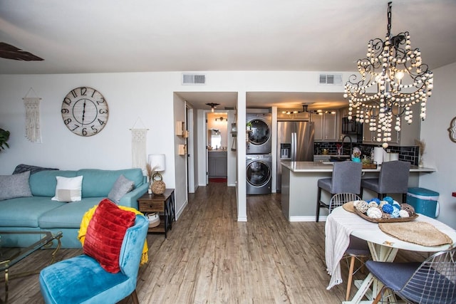 living room featuring stacked washer / dryer, wood-type flooring, and sink