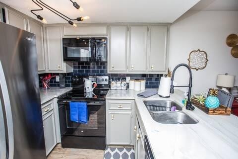 kitchen with tasteful backsplash, sink, and black appliances