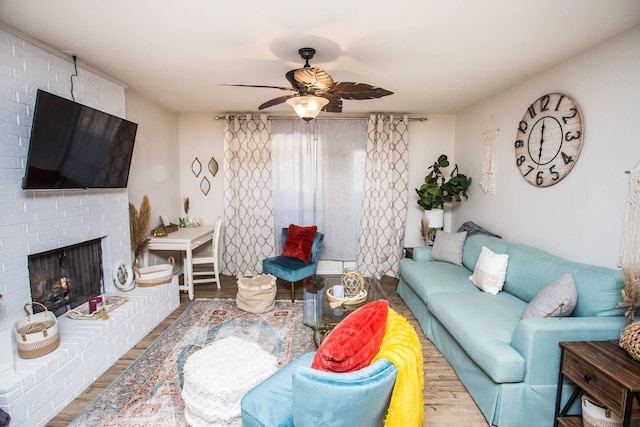 living room featuring wood-type flooring, a brick fireplace, and ceiling fan