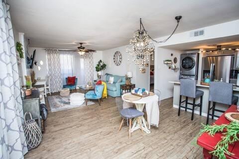 dining area with stacked washer and dryer, hardwood / wood-style flooring, and ceiling fan