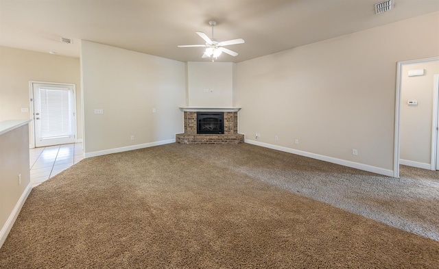 unfurnished living room featuring a brick fireplace, light carpet, and ceiling fan