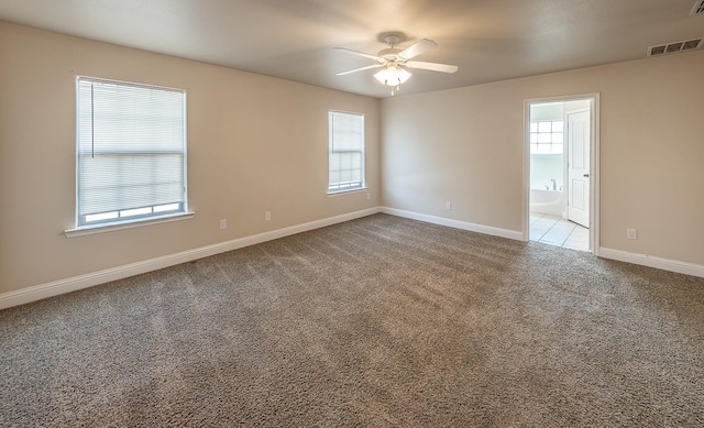 carpeted spare room featuring ceiling fan and a healthy amount of sunlight