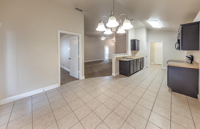 kitchen with sink, light tile patterned floors, stove, an inviting chandelier, and vaulted ceiling