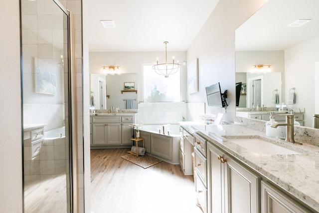 bathroom featuring independent shower and bath, vanity, hardwood / wood-style floors, and a notable chandelier