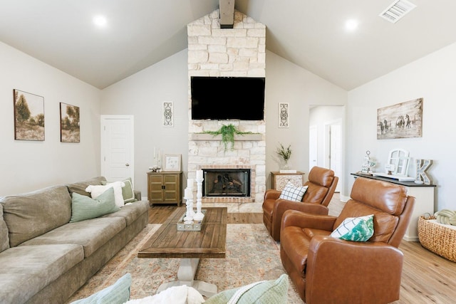 living room featuring beam ceiling, high vaulted ceiling, light wood-type flooring, and a fireplace