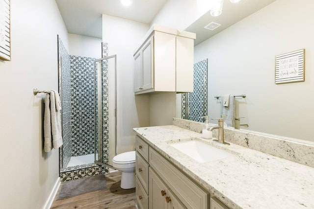 bathroom with vanity, wood-type flooring, a shower with shower door, and toilet