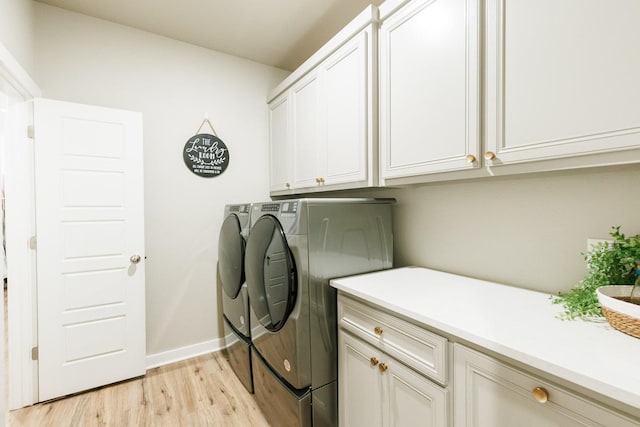 laundry room with independent washer and dryer, cabinets, and light hardwood / wood-style floors