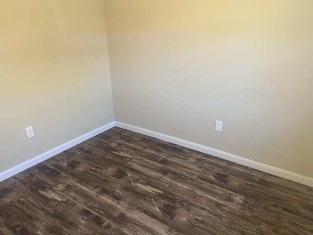 unfurnished room with baseboards and dark wood-style flooring