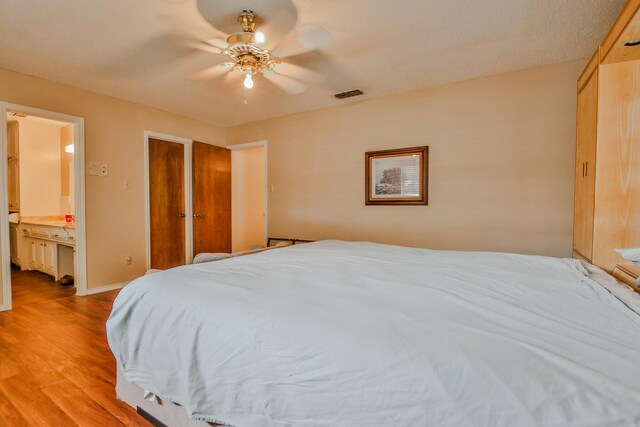 bedroom with connected bathroom, light hardwood / wood-style floors, and ceiling fan