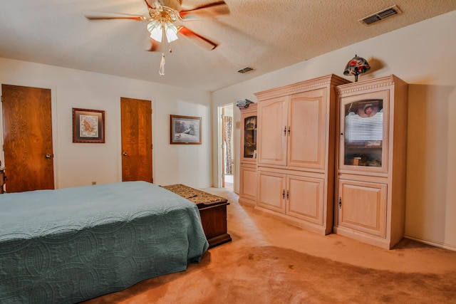 carpeted bedroom featuring ceiling fan and a textured ceiling