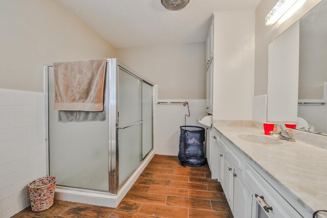 bathroom featuring vanity, tile walls, a textured ceiling, and walk in shower