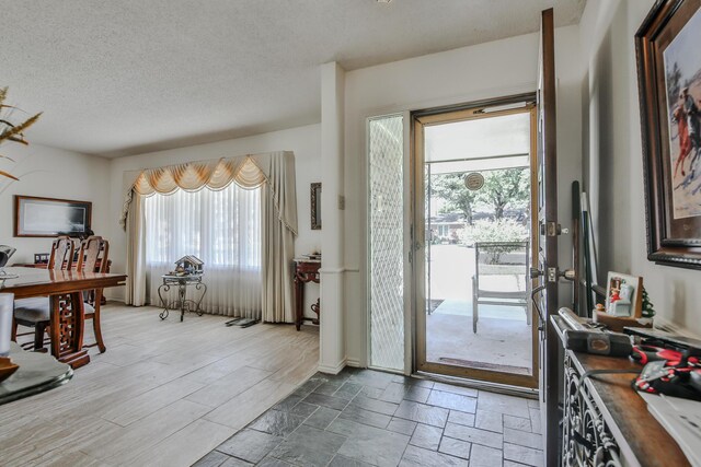 doorway to outside with a textured ceiling