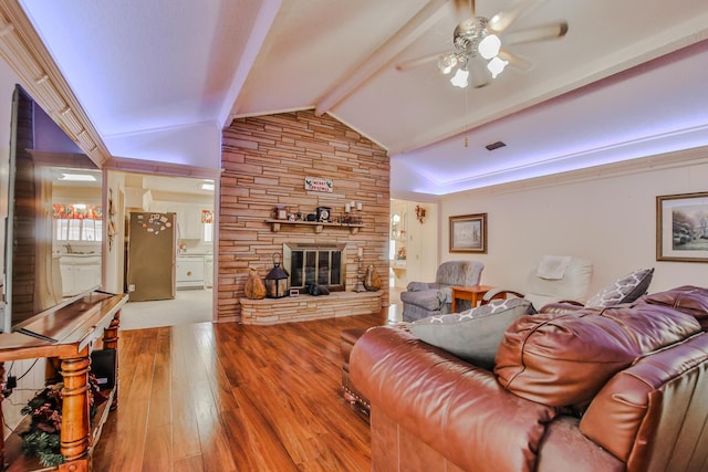 living room featuring vaulted ceiling with beams, a stone fireplace, light hardwood / wood-style floors, and ceiling fan