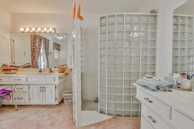 bathroom with walk in shower, vanity, and a textured ceiling