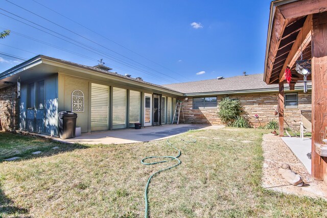 rear view of property featuring a lawn and a patio area