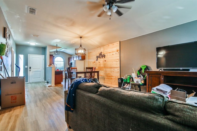living area with lofted ceiling, light wood-style floors, a ceiling fan, and visible vents