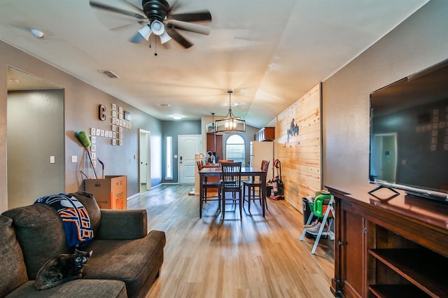 dining area featuring light wood finished floors, a ceiling fan, visible vents, and vaulted ceiling