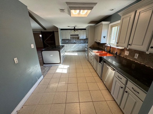 kitchen featuring light tile patterned flooring, sink, backsplash, stainless steel dishwasher, and a barn door