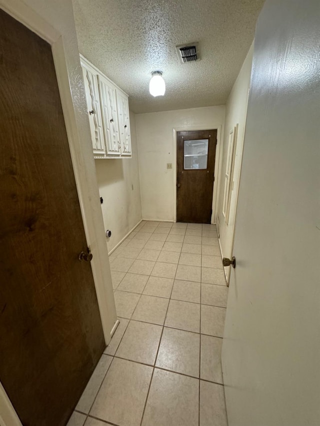 hall with light tile patterned flooring and a textured ceiling