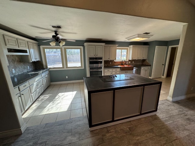 kitchen featuring sink, a center island, appliances with stainless steel finishes, ceiling fan, and backsplash
