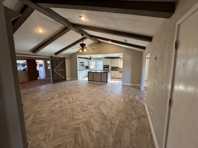 unfurnished living room featuring ceiling fan, light parquet flooring, a barn door, and lofted ceiling with beams