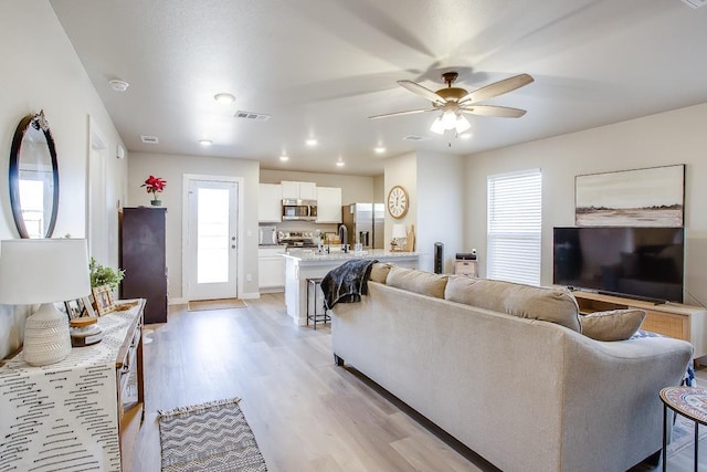 living room with ceiling fan, sink, and light hardwood / wood-style flooring