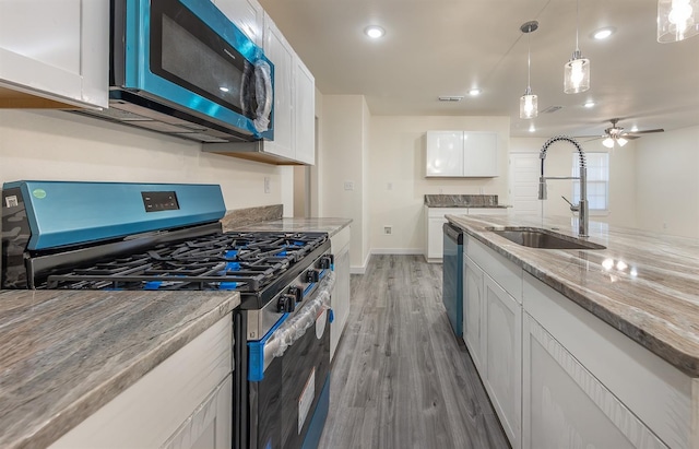 kitchen featuring sink, light stone counters, appliances with stainless steel finishes, pendant lighting, and white cabinets