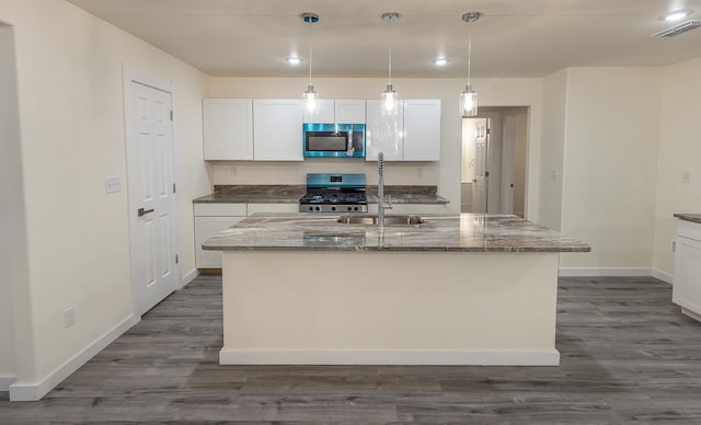 kitchen featuring appliances with stainless steel finishes, an island with sink, sink, dark stone countertops, and white cabinets