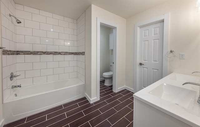 full bathroom with tiled shower / bath, vanity, toilet, and hardwood / wood-style floors