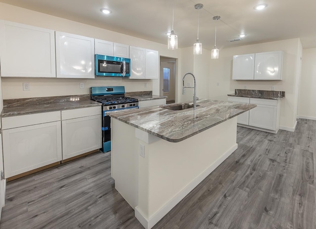 kitchen featuring white cabinetry, an island with sink, sink, and gas stove