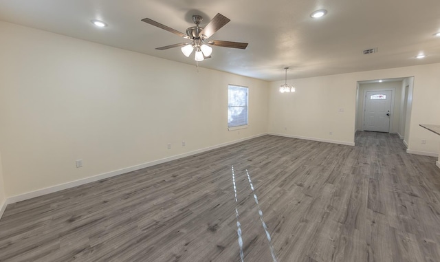 spare room featuring wood-type flooring and ceiling fan with notable chandelier