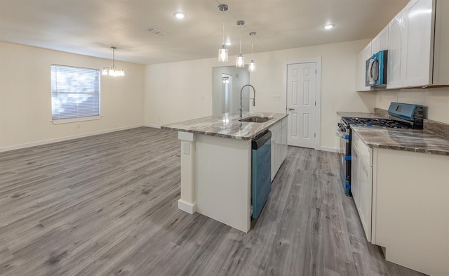 kitchen with an island with sink, sink, white cabinets, hanging light fixtures, and stainless steel gas range