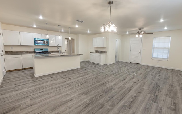 kitchen featuring pendant lighting, sink, stainless steel appliances, white cabinets, and a center island with sink