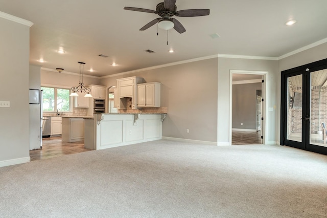 kitchen featuring a breakfast bar area, white cabinets, backsplash, hanging light fixtures, and light colored carpet