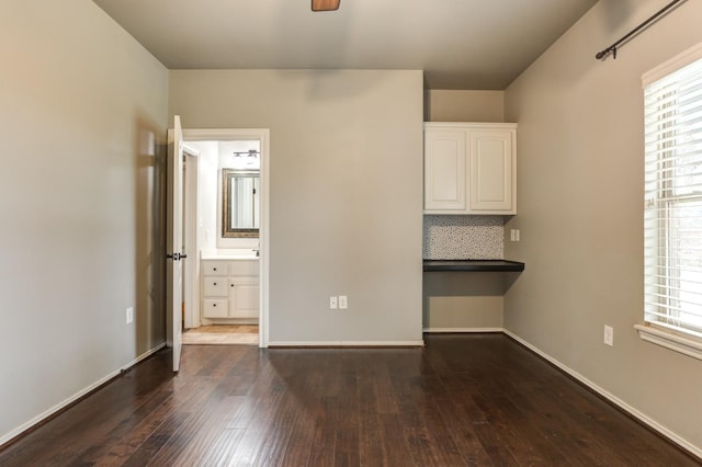 unfurnished bedroom featuring ensuite bathroom and dark wood-type flooring