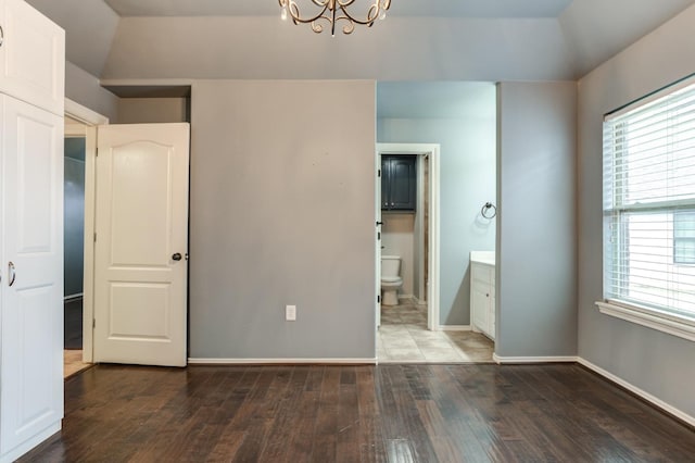 unfurnished bedroom with an inviting chandelier, dark hardwood / wood-style flooring, and ensuite bath