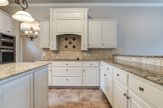 kitchen featuring tasteful backsplash, white cabinetry, pendant lighting, and double oven