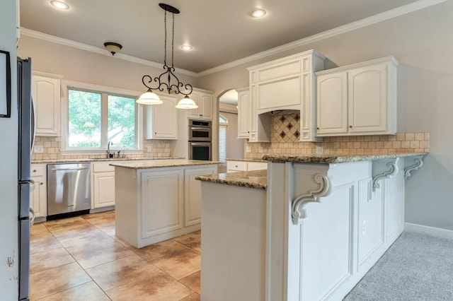 kitchen featuring white cabinetry, hanging light fixtures, a kitchen island, stainless steel appliances, and light stone countertops