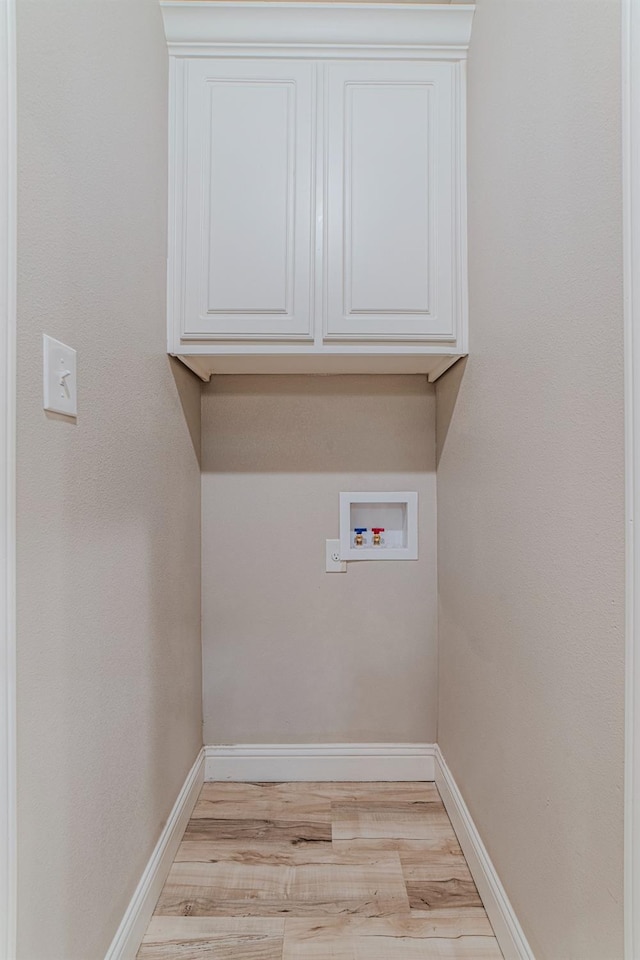 laundry area with hookup for a washing machine, cabinets, and light wood-type flooring