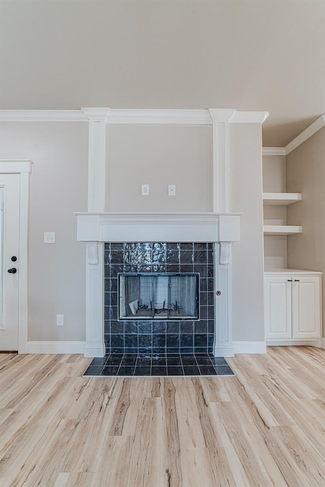 interior details featuring hardwood / wood-style flooring, crown molding, built in features, and a tile fireplace