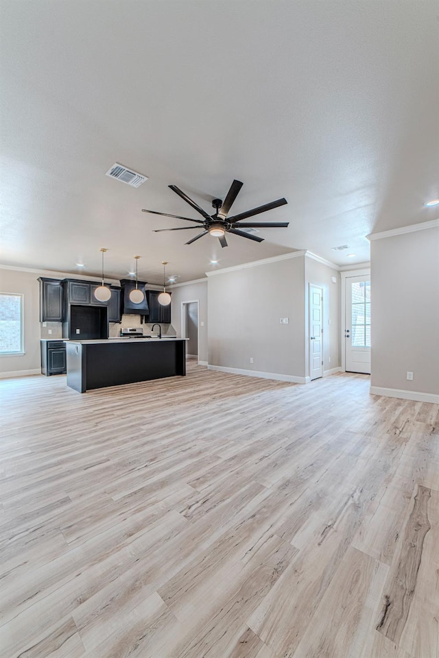 unfurnished living room featuring ceiling fan, ornamental molding, light hardwood / wood-style floors, and a wealth of natural light