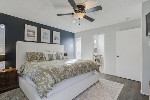 bedroom with dark hardwood / wood-style floors, ceiling fan, connected bathroom, and a textured ceiling