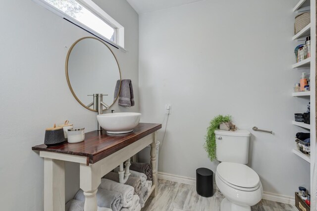 bathroom featuring wood-type flooring, toilet, and sink