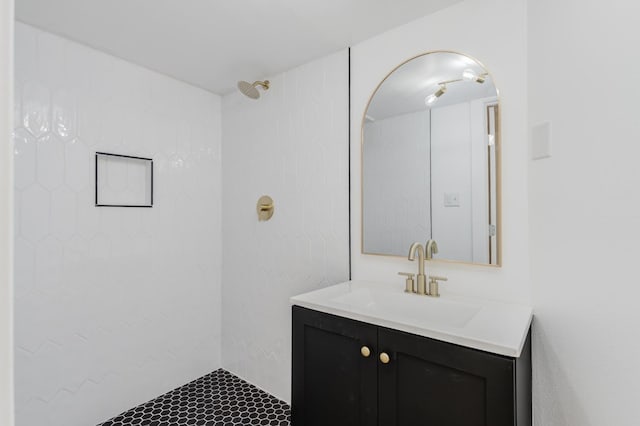 bathroom with tiled shower and vanity