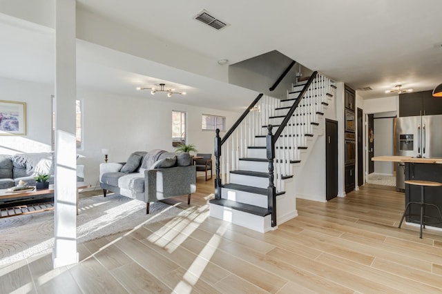 staircase with an inviting chandelier and wood-type flooring