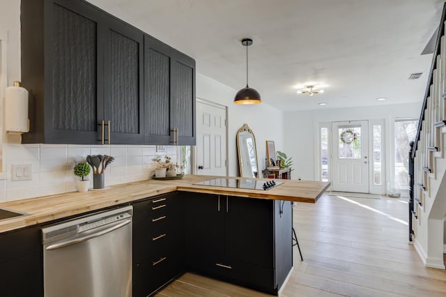 kitchen featuring a breakfast bar, butcher block countertops, decorative light fixtures, black electric cooktop, and dishwasher