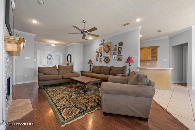 10401 Elgin Ave, Lubbock, TX 79423 - living room with ceiling fan, a textured ceiling, crown molding, wood finished floors, and a tiled fireplace