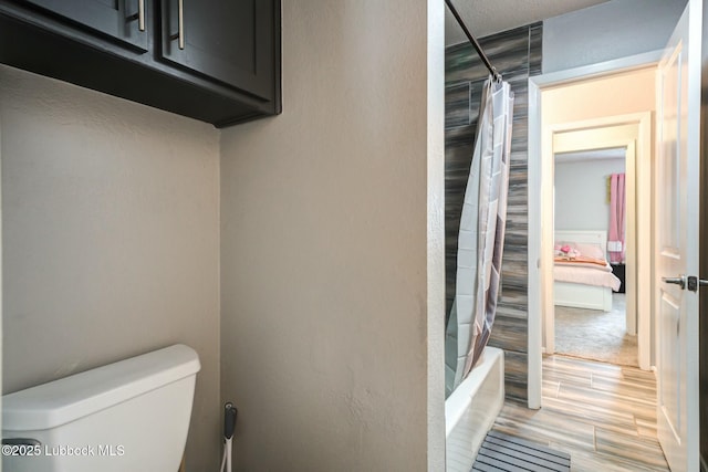 5734 92nd St, Lubbock, TX 79424 - bathroom featuring shower / bath combo with shower curtain, toilet, and wood finished floors
